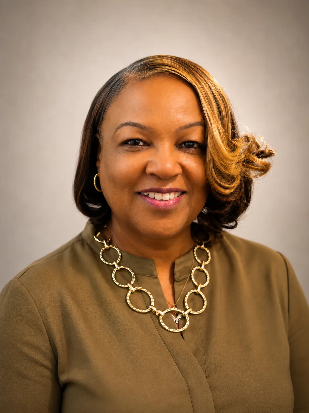 Rev. Judy Tyler smiles in a professional portrait wearing an olive-green blouse.