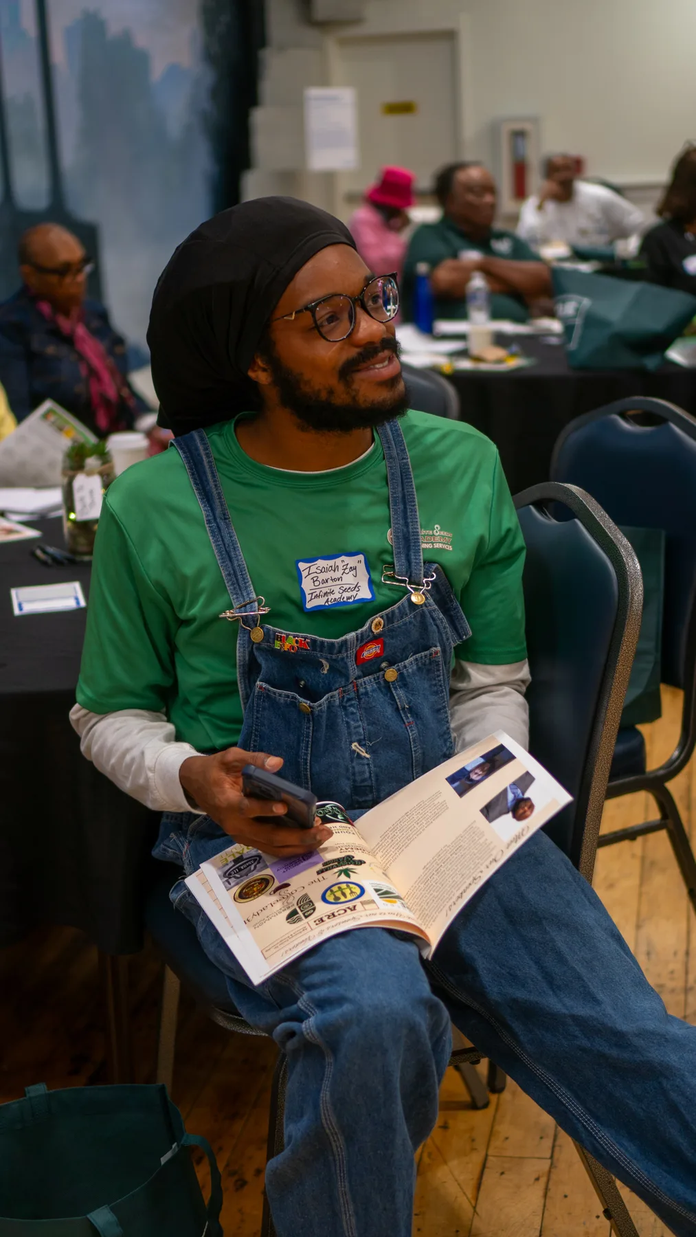A person in work overalls reads a printed growing guide.