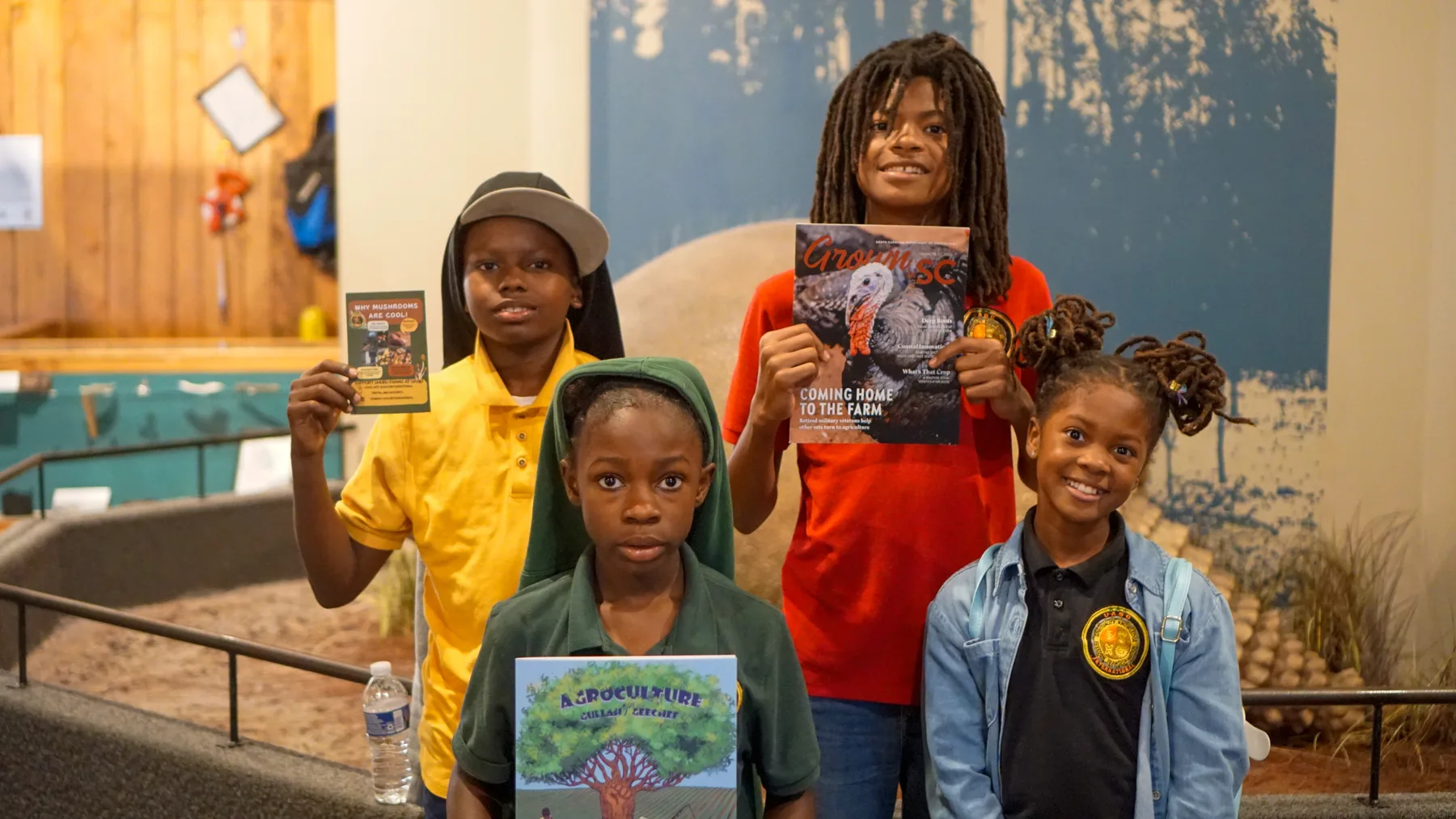 Four young people hold books about agriculture and rural life.