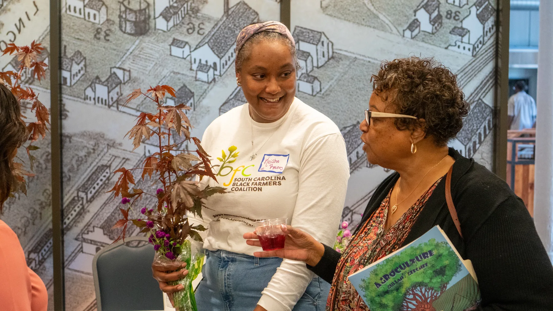 People talk around a plant display.