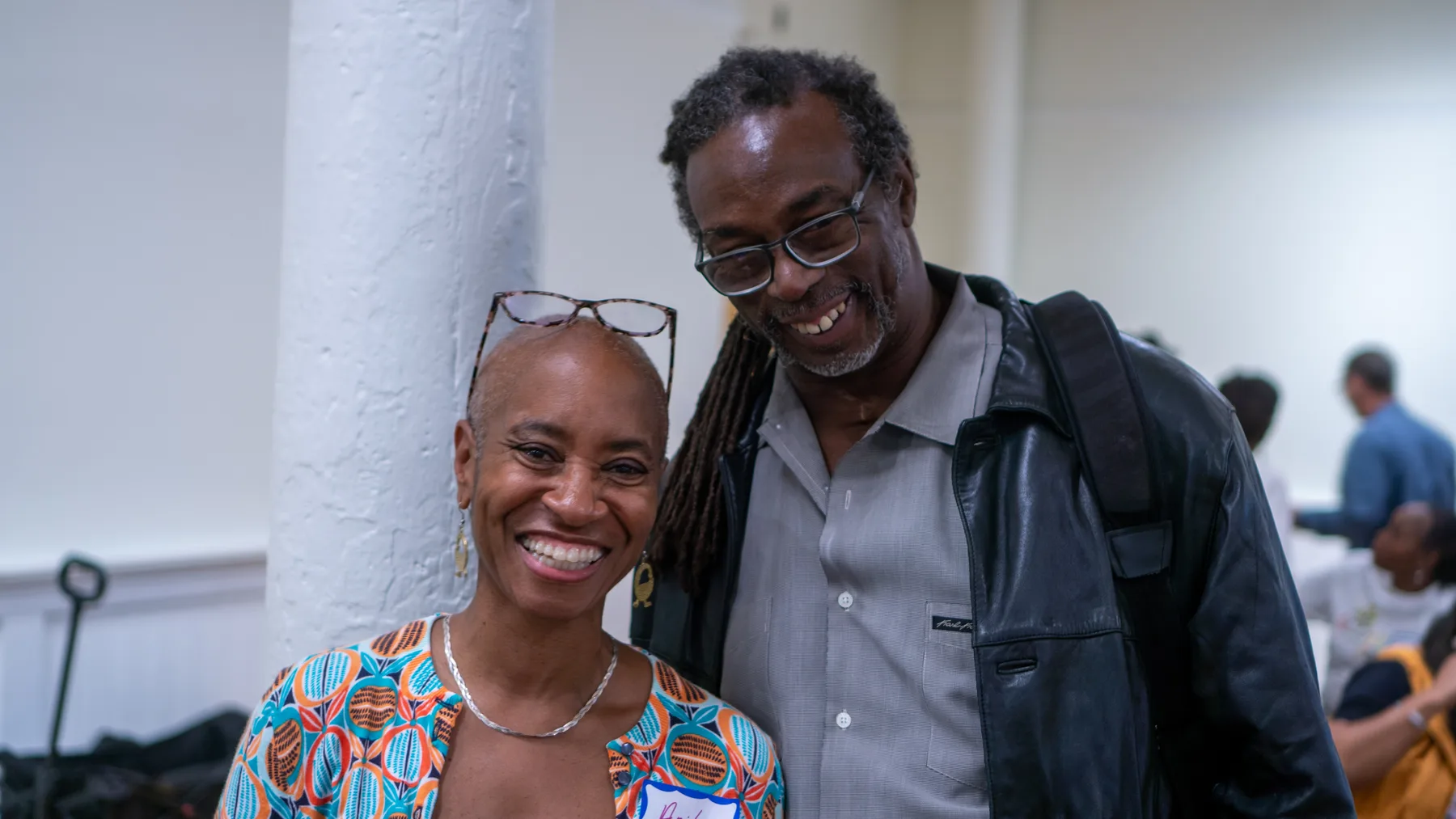 Two people stand together and smile at a community gathering.