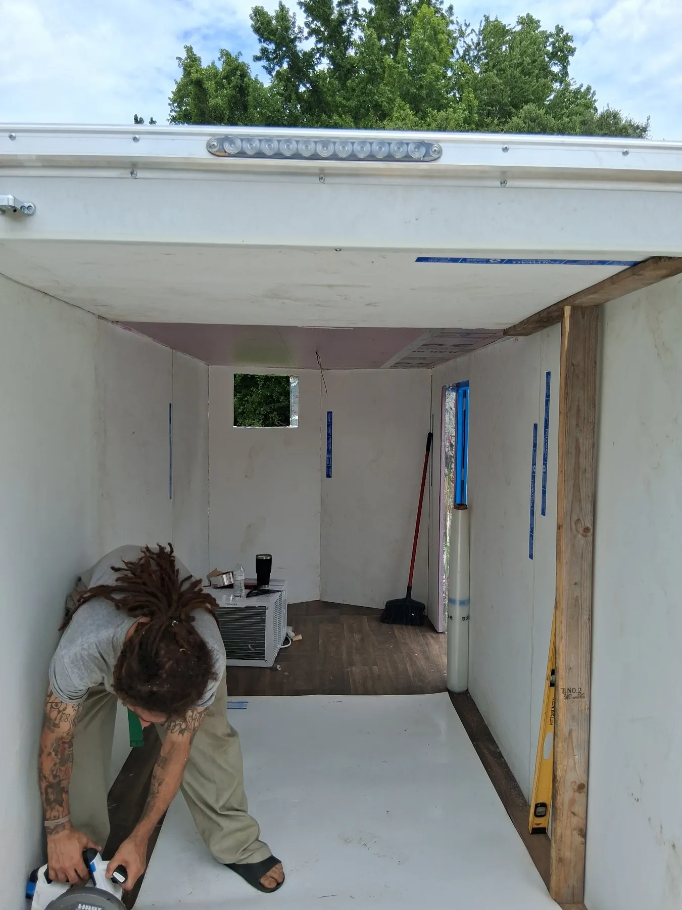 The insulated interior of the cold-storage trailer with a window air-conditioning unit mounted high on the end wall.