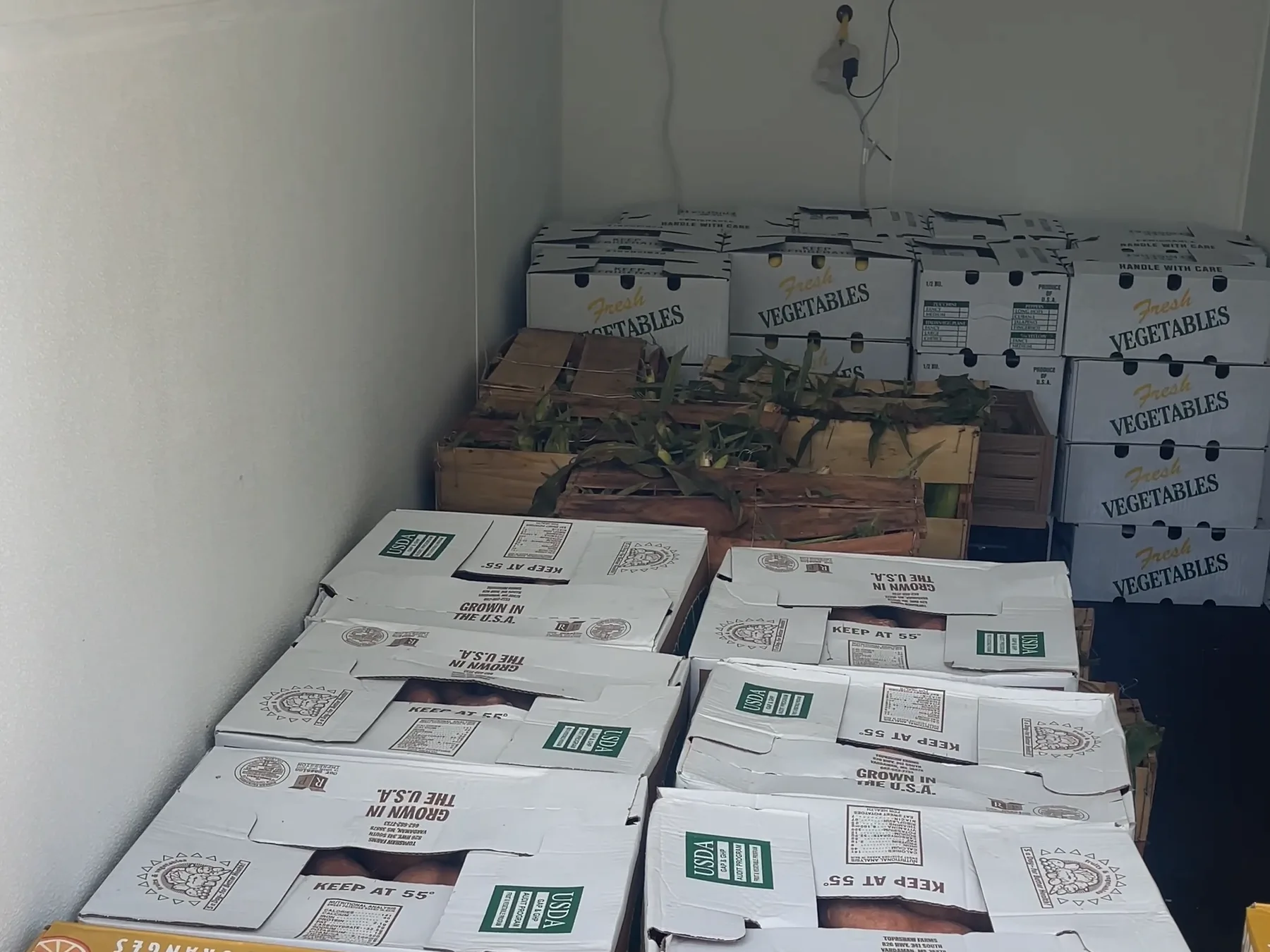 Stacked produce boxes fill the white insulated interior of one of the cold-storage units.