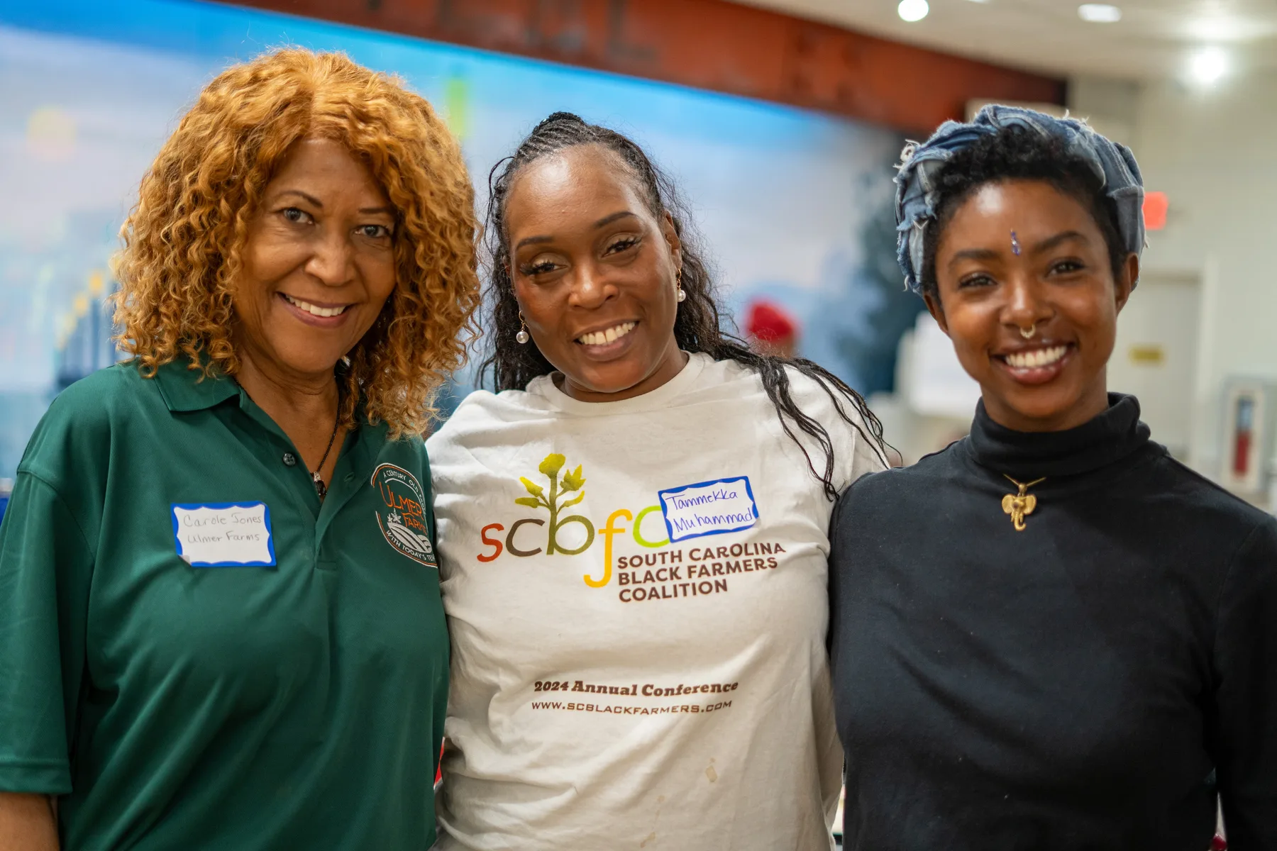 Three people smile together at a community gathering.