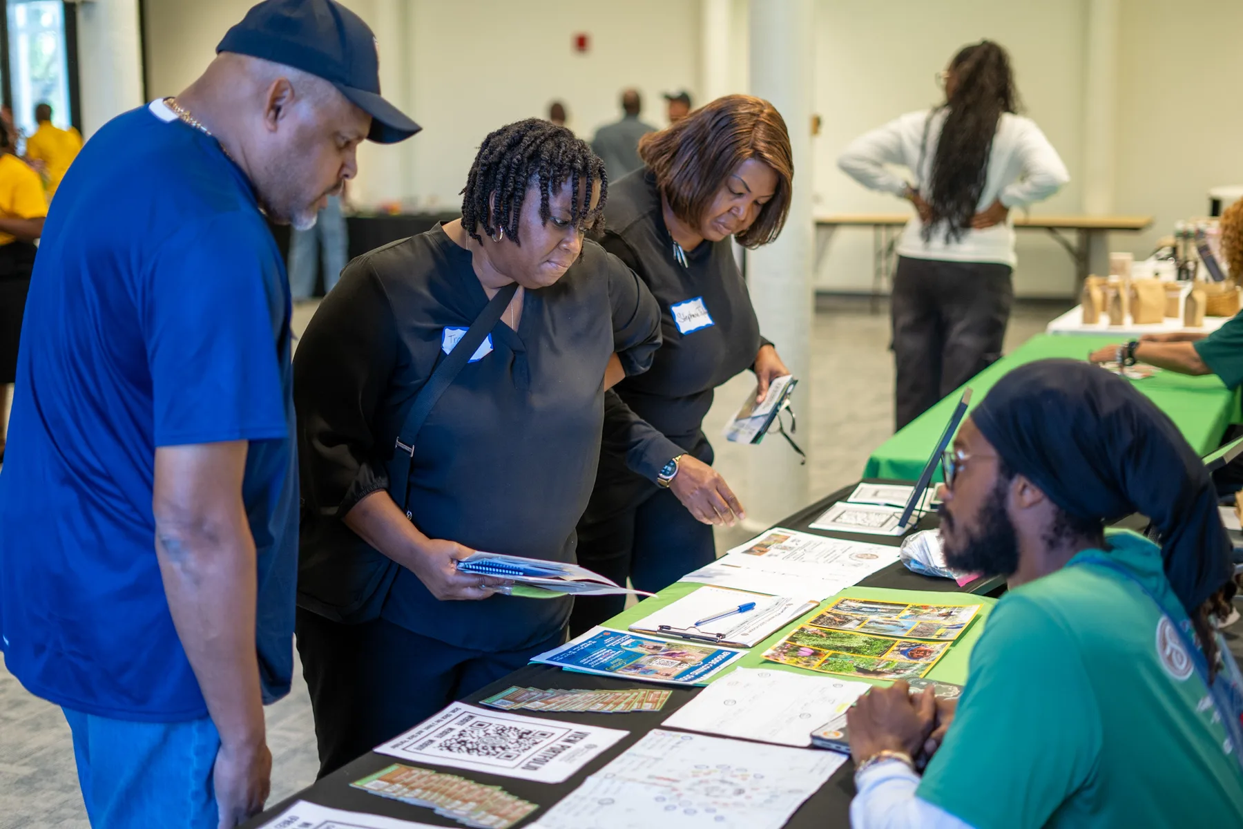 People look over printed materials spread across an information table.