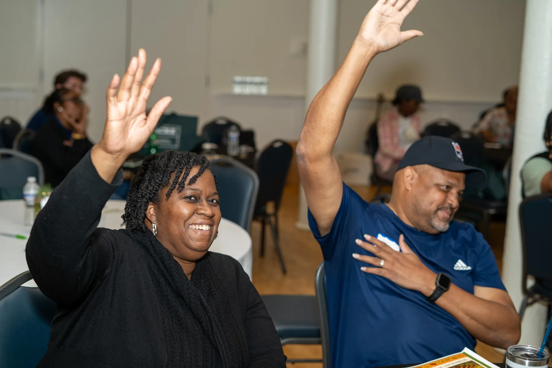 Two people raise their hands and smile during a session.