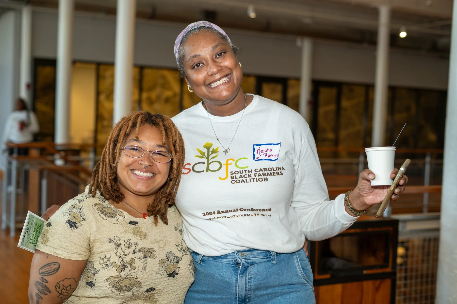 Three people smile together at a community gathering.