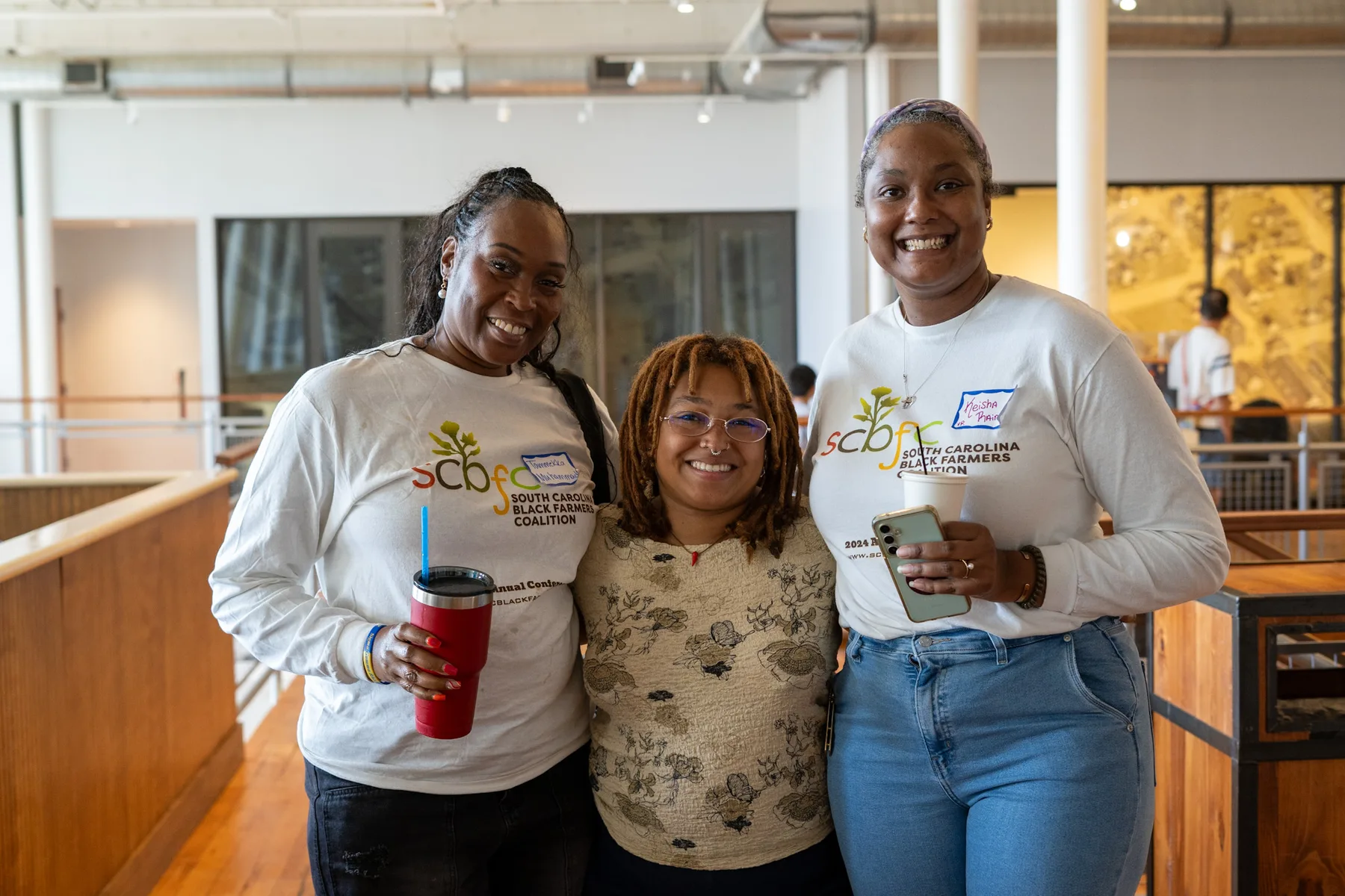 Three people smile together at a community gathering.